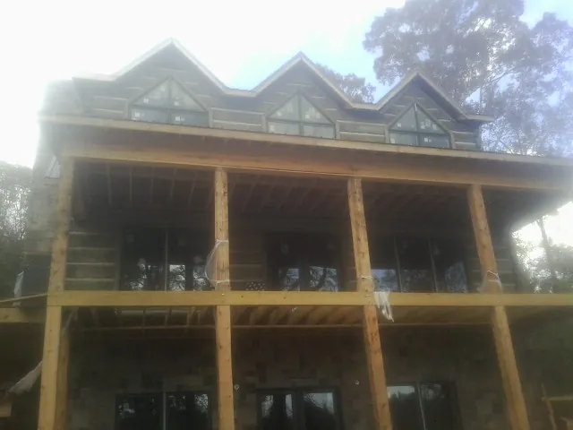 Dormers and porch framing on a large log home under construction — Roof Coating work by our crew in Brainard